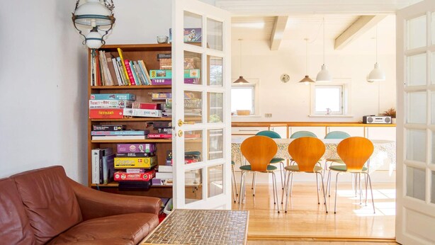 A living room with a brown leather sofa, a wooden coffee table, and a bookshelf filled with board games.