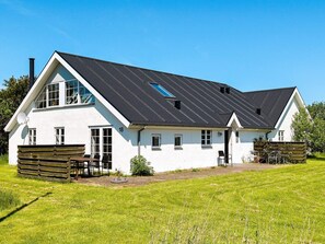 A white house with a black roof, number 18, and a small garden with wooden benches. - 10 Person Holiday Home in Thisted (Thisted)