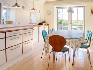 A dining area with a round table, chairs, and a kitchen area with cabinets and a counter.