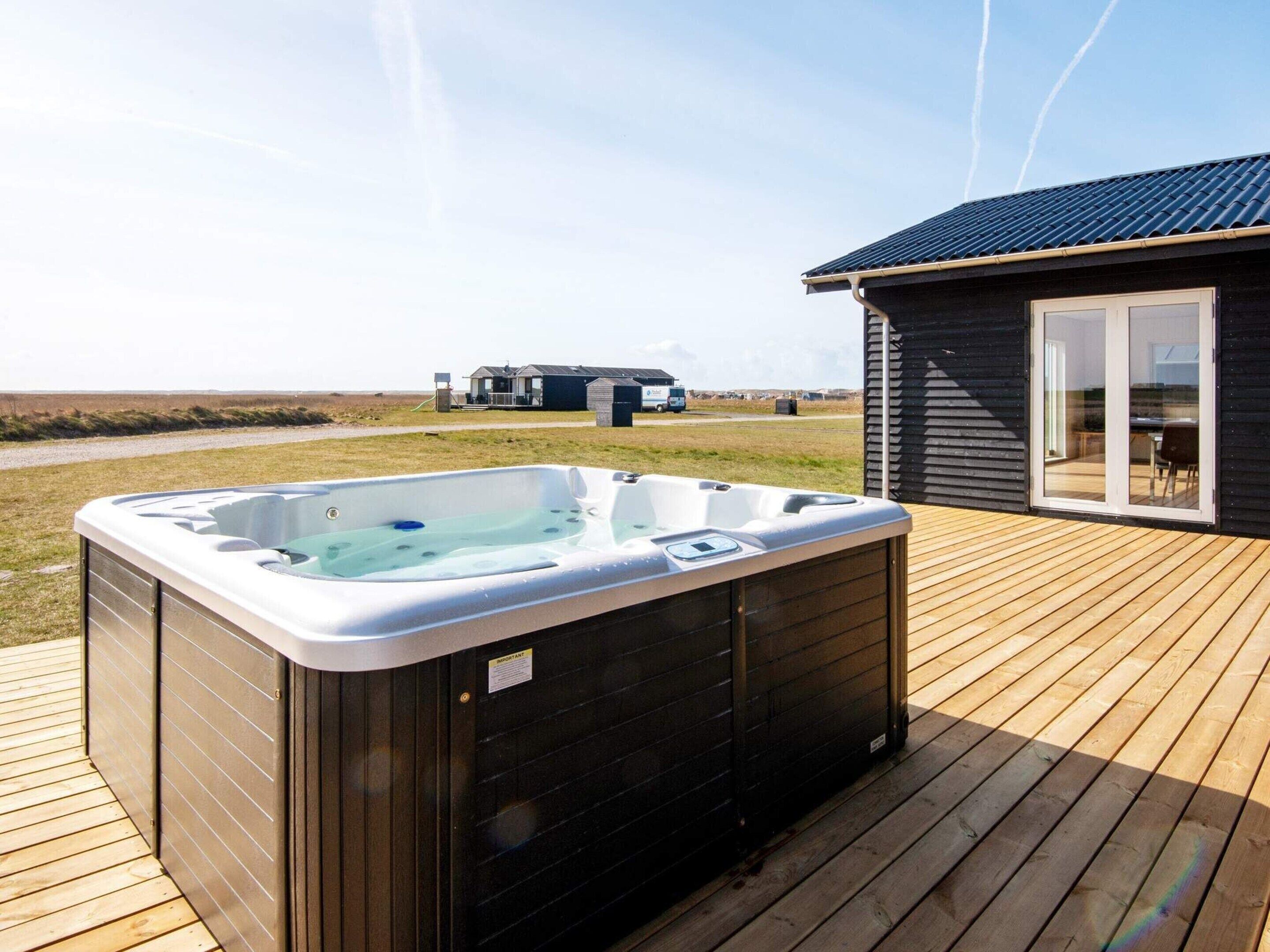 A hot tub on a wooden deck with a house in the background.