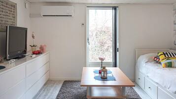 Un dormitorio con cama, televisor, escritorio y ventana.