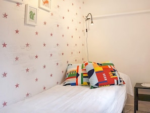 A bedroom with a bed, colorful pillows, a wall-mounted lamp, and a small table with a lamp. - 4 Person Holiday Home in Lysekil (Lysekil)