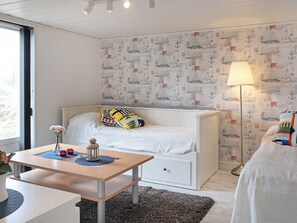 Un dormitorio con cama, mesita de noche, lámpara y un papel tapiz con motivos náuticos.