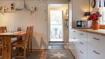 Una cocina equipada con microondas, estufa y lavaplatos. Hay una mesa de comedor de madera con sillas y un tapete con estampado de estrellas.