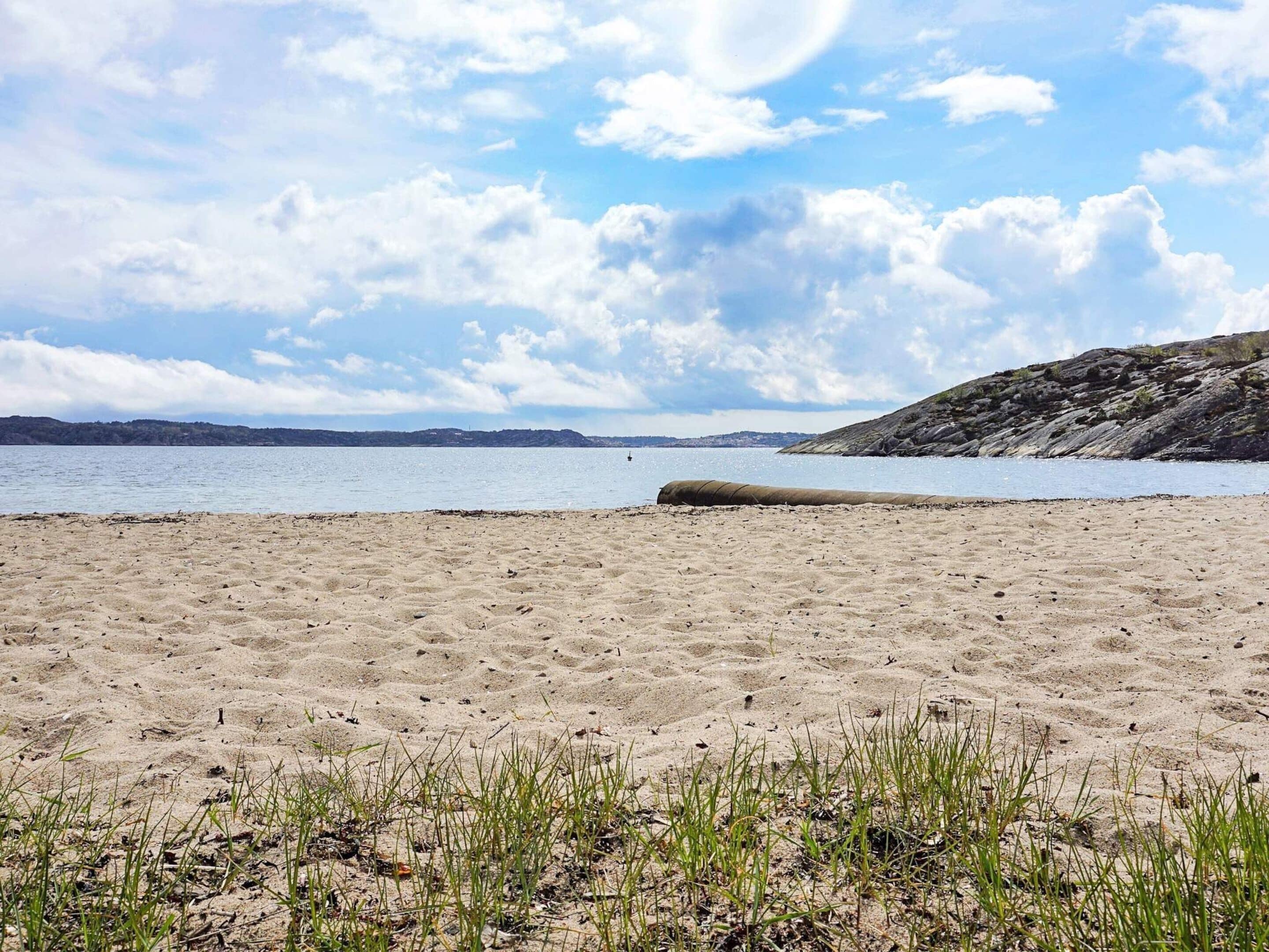 A sandy beach with a clear sky and distant hills.