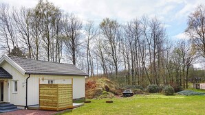 Ein eingeschossiges Haus mit geneigtem Dach, einer Holztür zur Garage und einer kleinen Veranda.
