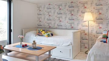 A bedroom with a bed, bedside table, lamp, and nautical-themed wallpaper.