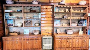 A wooden cabin interior with built-in shelves displaying books, pottery, and decorative items.
