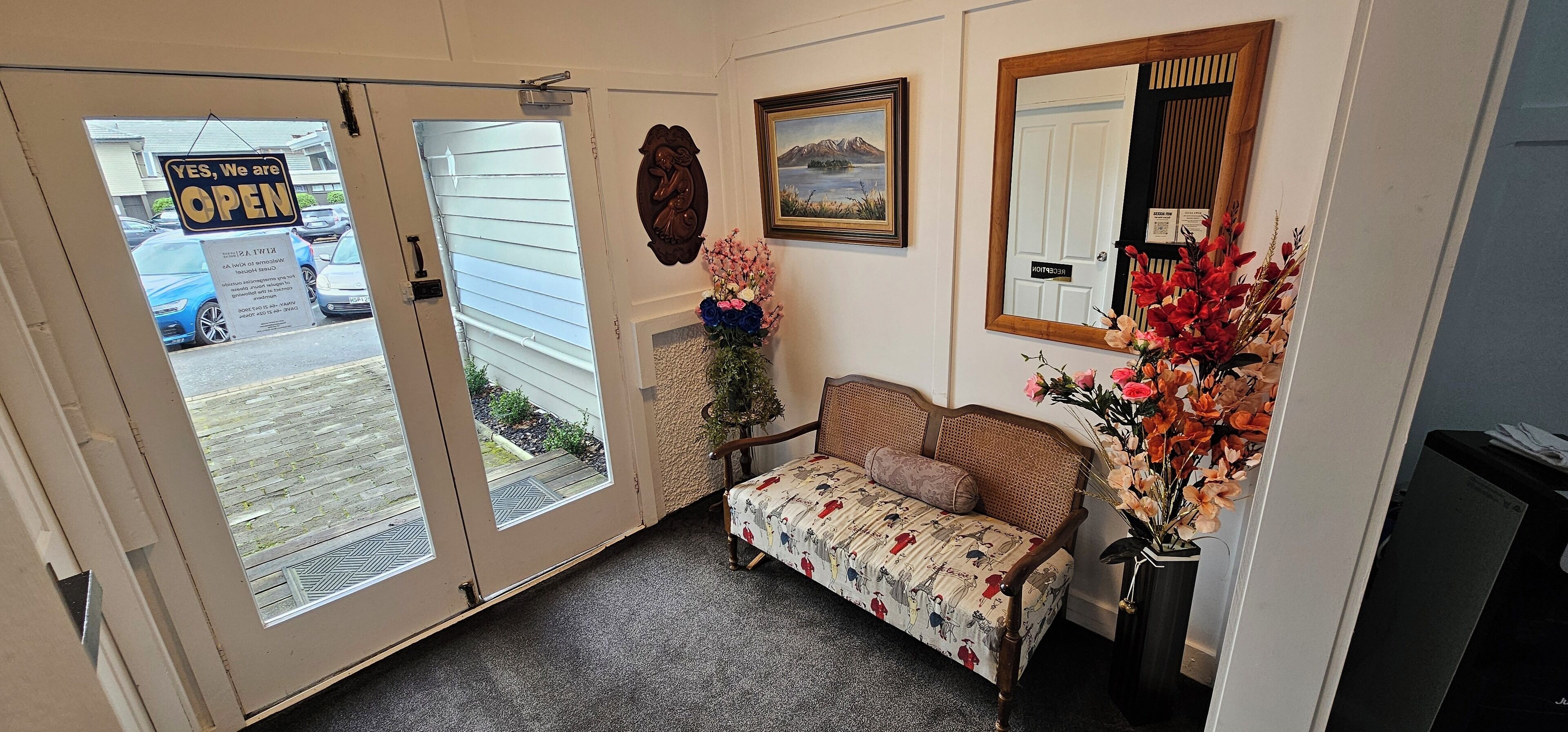 A reception area with a bench, a floral arrangement, and a painting on the wall.