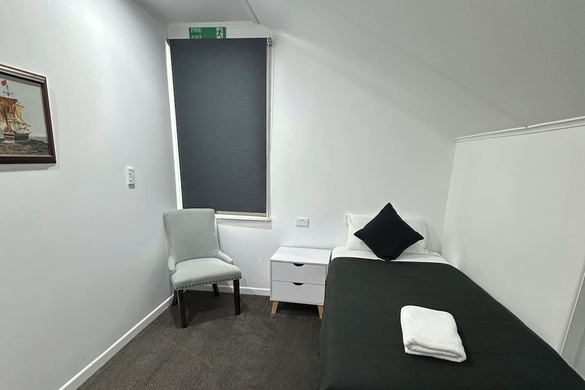 Une chambre d’hôtel avec un lit, une chaise, un bureau et une fenêtre.
