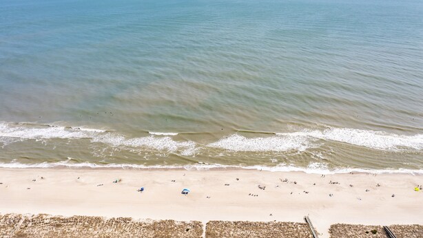 A beach with waves, a sandy shore, and a clear sky. - Pearl Paradise: with elevator & golf cart included! 2 blocks to beach.  (Carolina Beach)