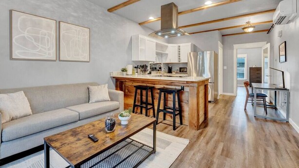 A modern kitchen with wooden beams, a central island with stools, and a dining area with a table and chairs. - DT Action! | Extended stay | Work, Play, & Relax! (Tacoma)