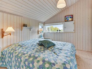 A bedroom with a large bed, two wall-mounted lamps, a window with a view, and a painting on the wall. - 5 Star Holiday Home in Nordborg (Nordborg)