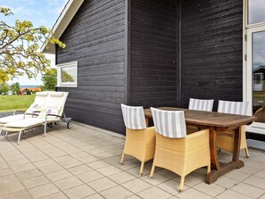 An outdoor seating area with a table and chairs, a lounge chair, and a small cart. - 5 Star Holiday Home in Nordborg (Nordborg)