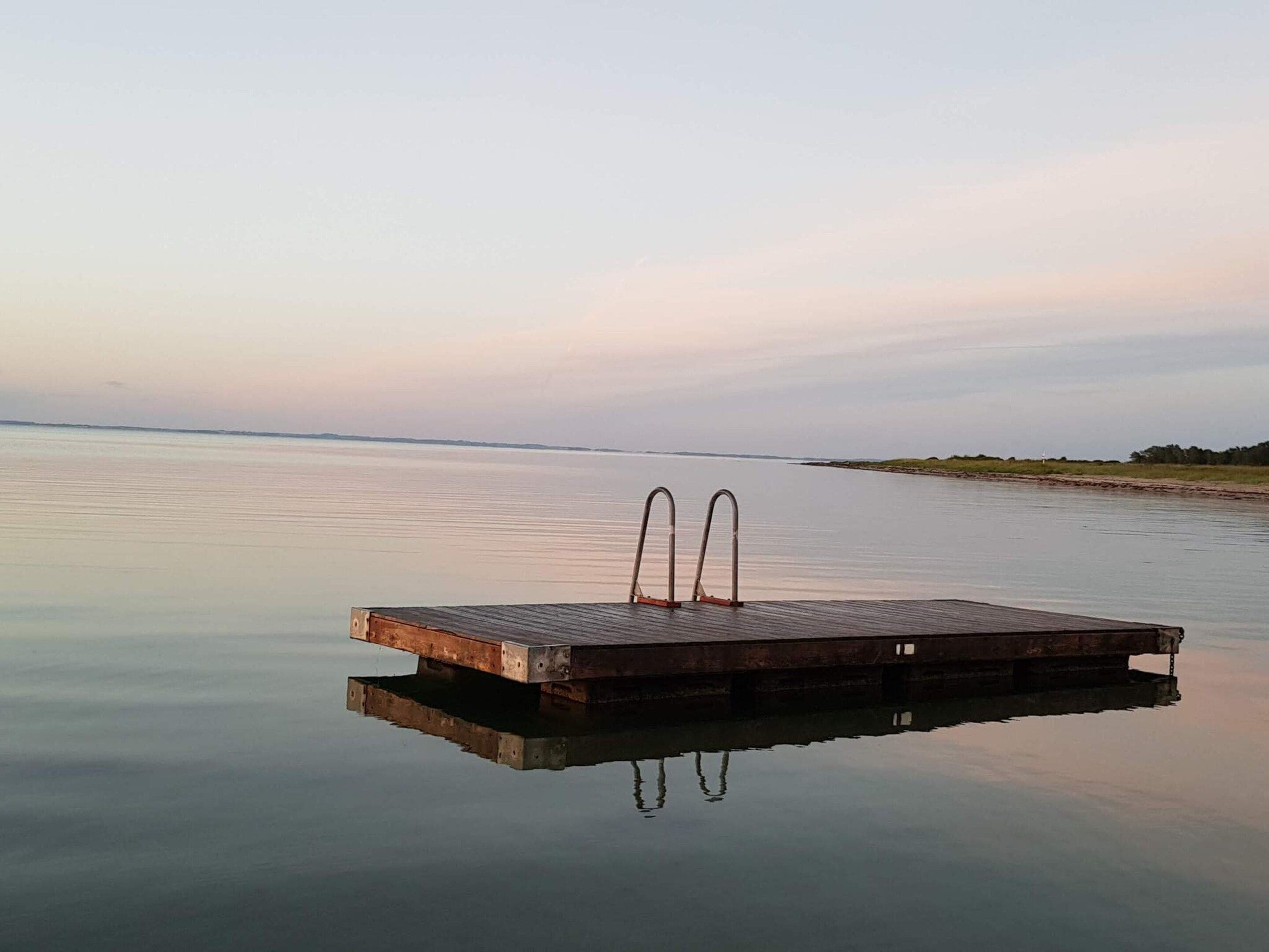 Een houten steiger die zich uitstrekt over kalm water, onder een heldere lucht.