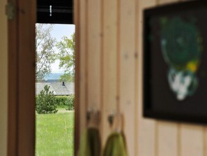 Una puerta que da a un cuarto con vista a un espacio verde y un edificio con tejado inclinado.