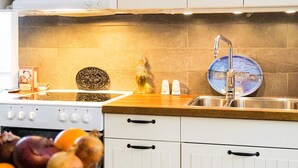 A kitchen with a stove, sink, and white cabinets. There are salt and pepper shakers, a decorative plate, and a bottle of oil on the counter. - 5 Person Holiday Home in Flen (Flen)
