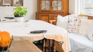 A cozy room with a wooden cabinet, a dining table with a white tablecloth, and a sofa with patterned cushions. - 5 Person Holiday Home in Flen (Flen)