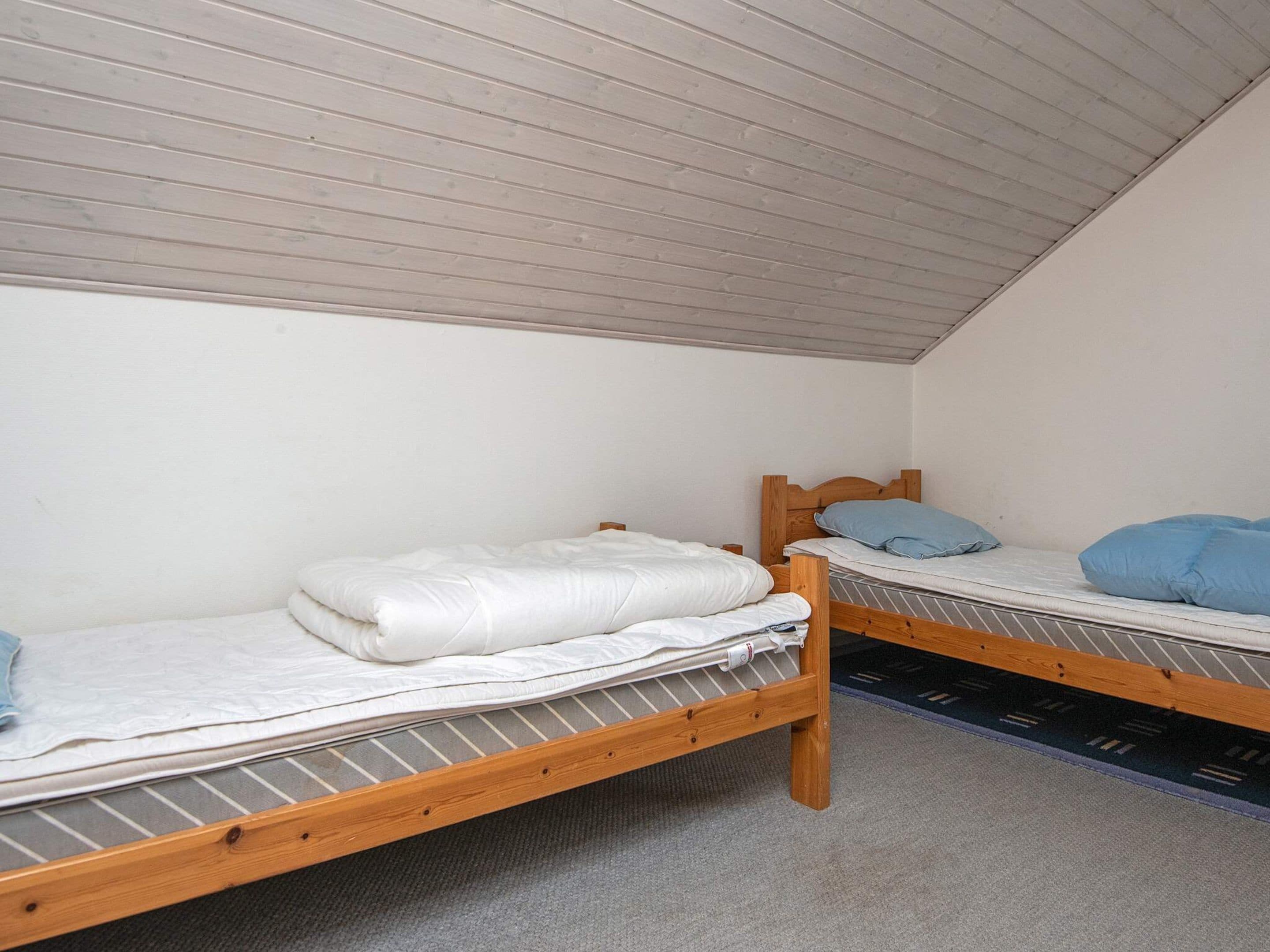 Une petite pièce avec deux lits superposés en bois, chacun étant équipé d’un matelas et d’oreillers.