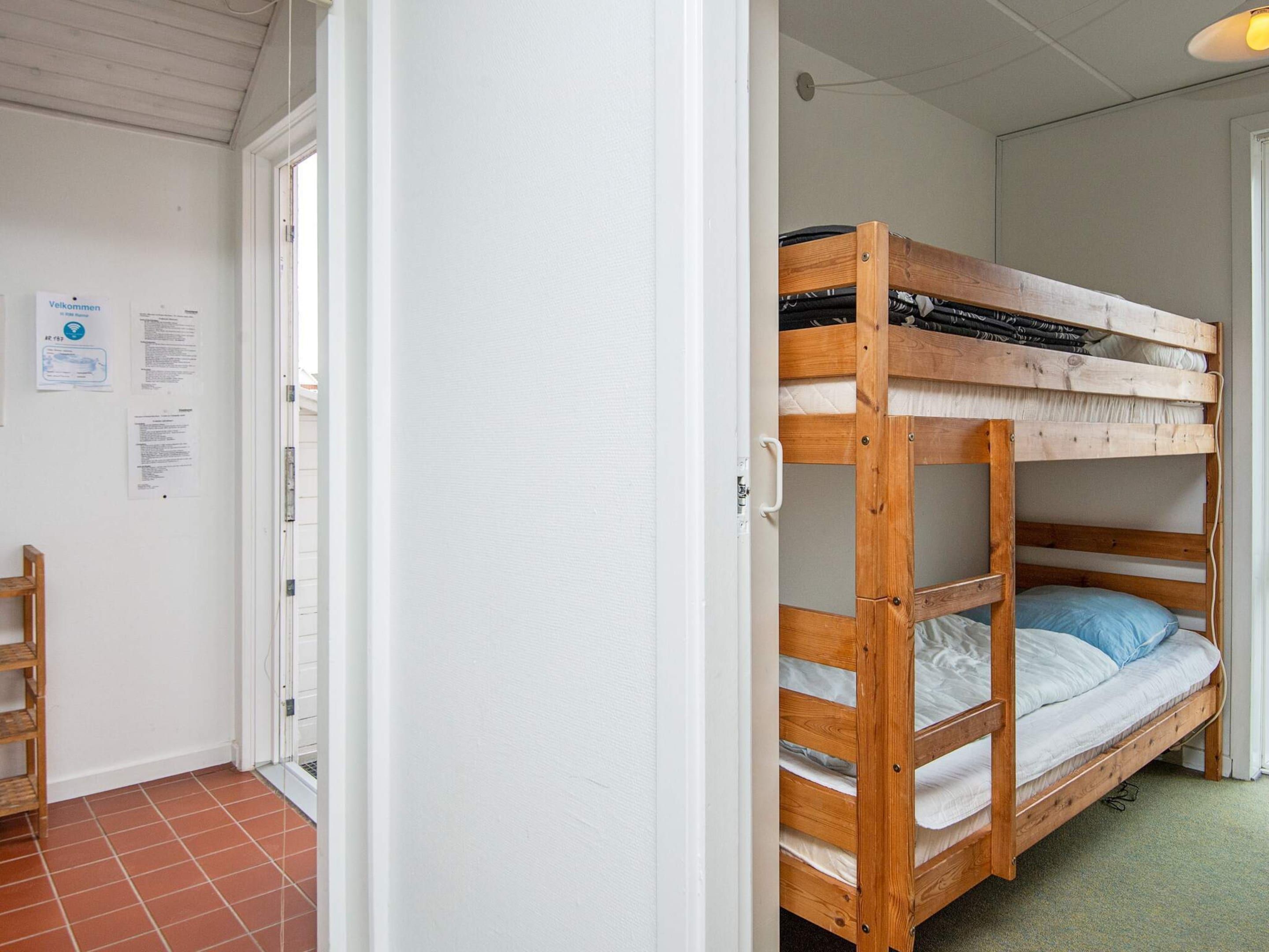 A room with a bunk bed, a wooden chair, and a door leading to another room.
