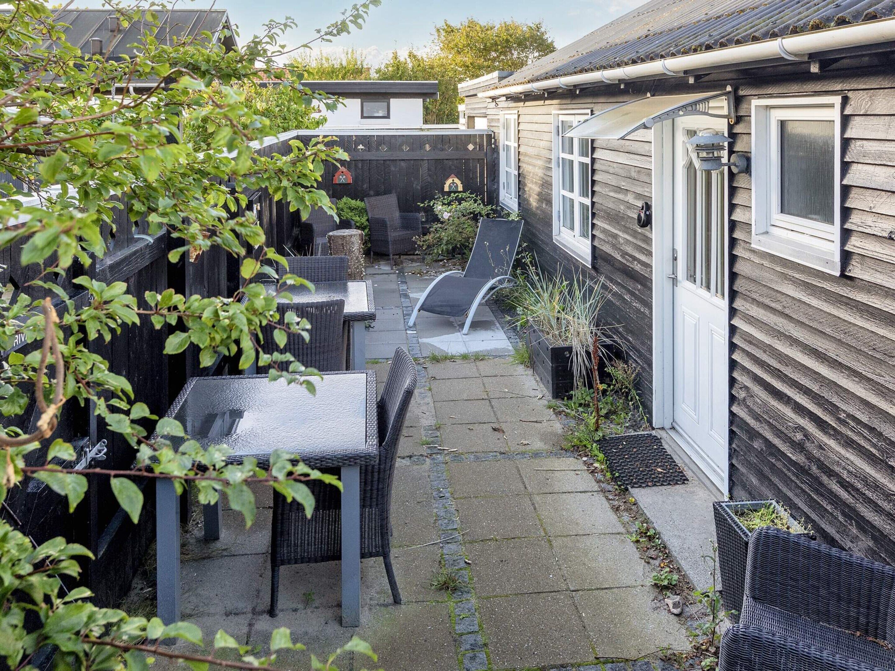 A patio area with outdoor furniture, a small garden, and a wooden house.