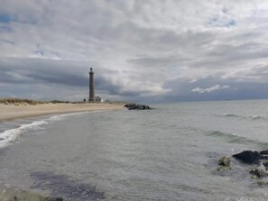 A coastal scene with a lighthouse, beach, and ocean.