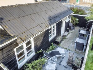 A residential building with a sloped roof, a visible window, and a paved patio area with outdoor furniture. - 4 Star Holiday Home in Skagen (Skagen)