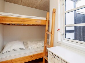A bunk bed with a wooden ladder, a white mattress, and a white pillow. There is a window with a view of a wooden fence outside. - 4 Star Holiday Home in Skagen (Skagen)