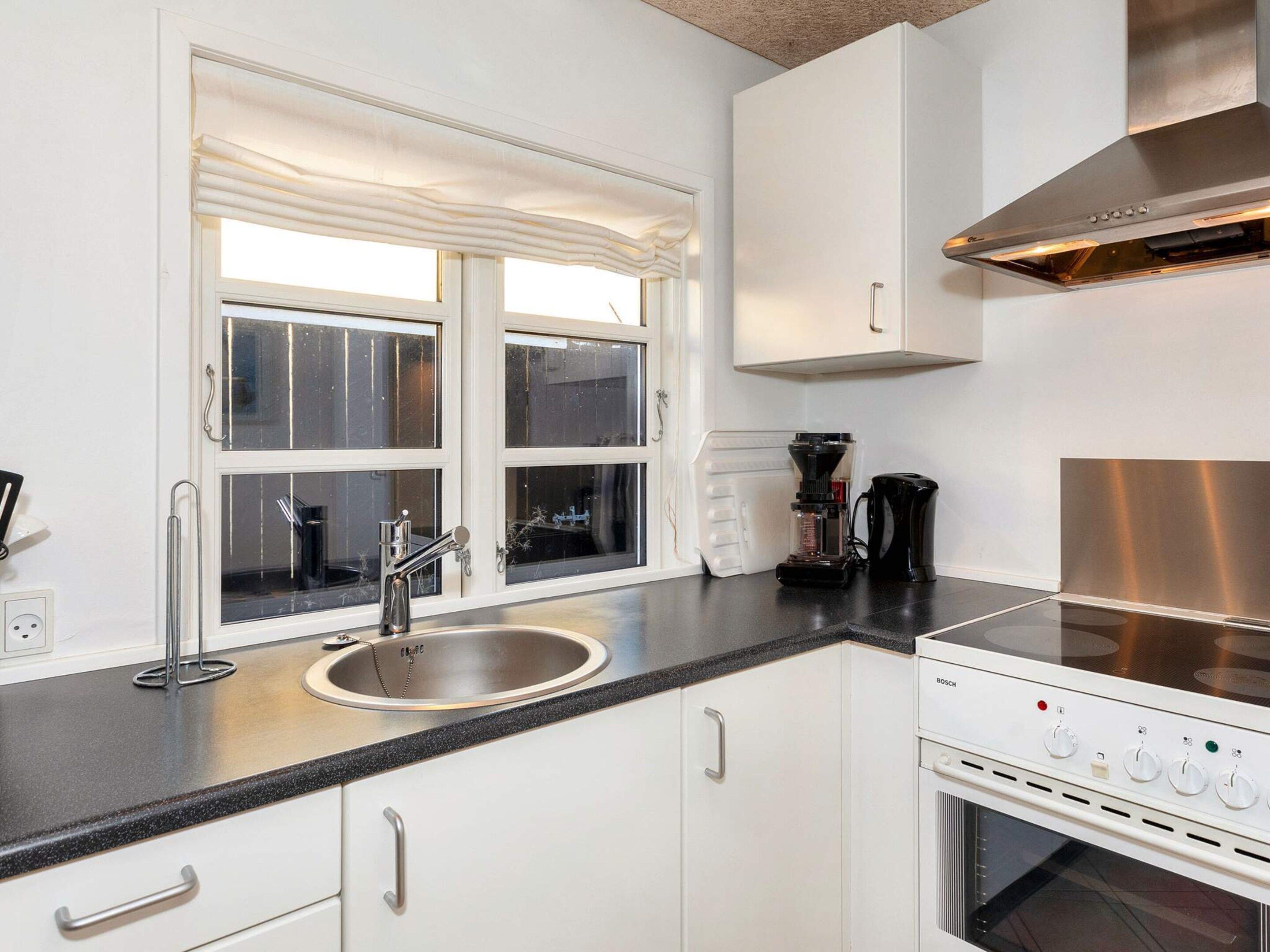 A modern kitchen with a stainless steel sink, a coffee maker, and a built-in oven.