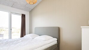 Un dormitorio con cama, puerta corrediza de vidrio y lámpara en el techo.