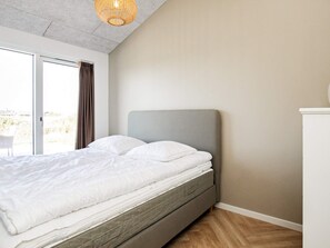 A bedroom with a bed, a sliding glass door, and a ceiling light fixture. - 5 Star Holiday Home in Hjorring (Hjørring)