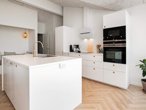 A modern kitchen with white cabinetry, a central island, and a built-in oven. - 5 Star Holiday Home in Hjorring (Hjørring)