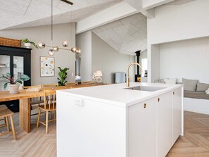 Una cocina moderna con una isla central, una mesa de comedor de madera y sillas.