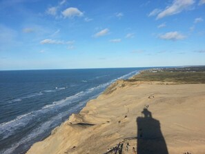 Un paisaje costero con una playa arenosa, olas del océano y cielo despejado.