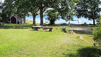 Un área de picnic con banco, mesa y un cobertizo pequeño.