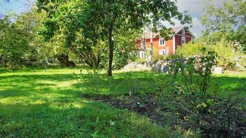 A red building with a stone wall and a grassy area with trees.
