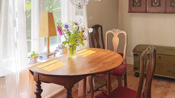 Un comedor con mesa de madera, sillas, una araña y un aparador.