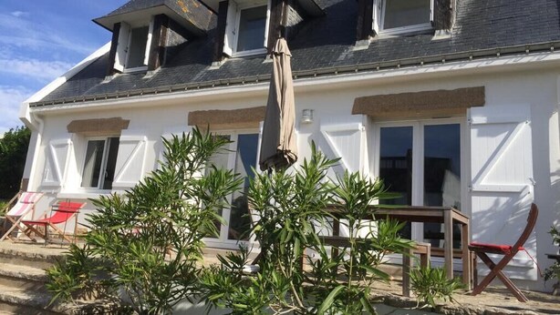 Una casa de dos pisos con fachada blanca, múltiples ventanas y un balcón.