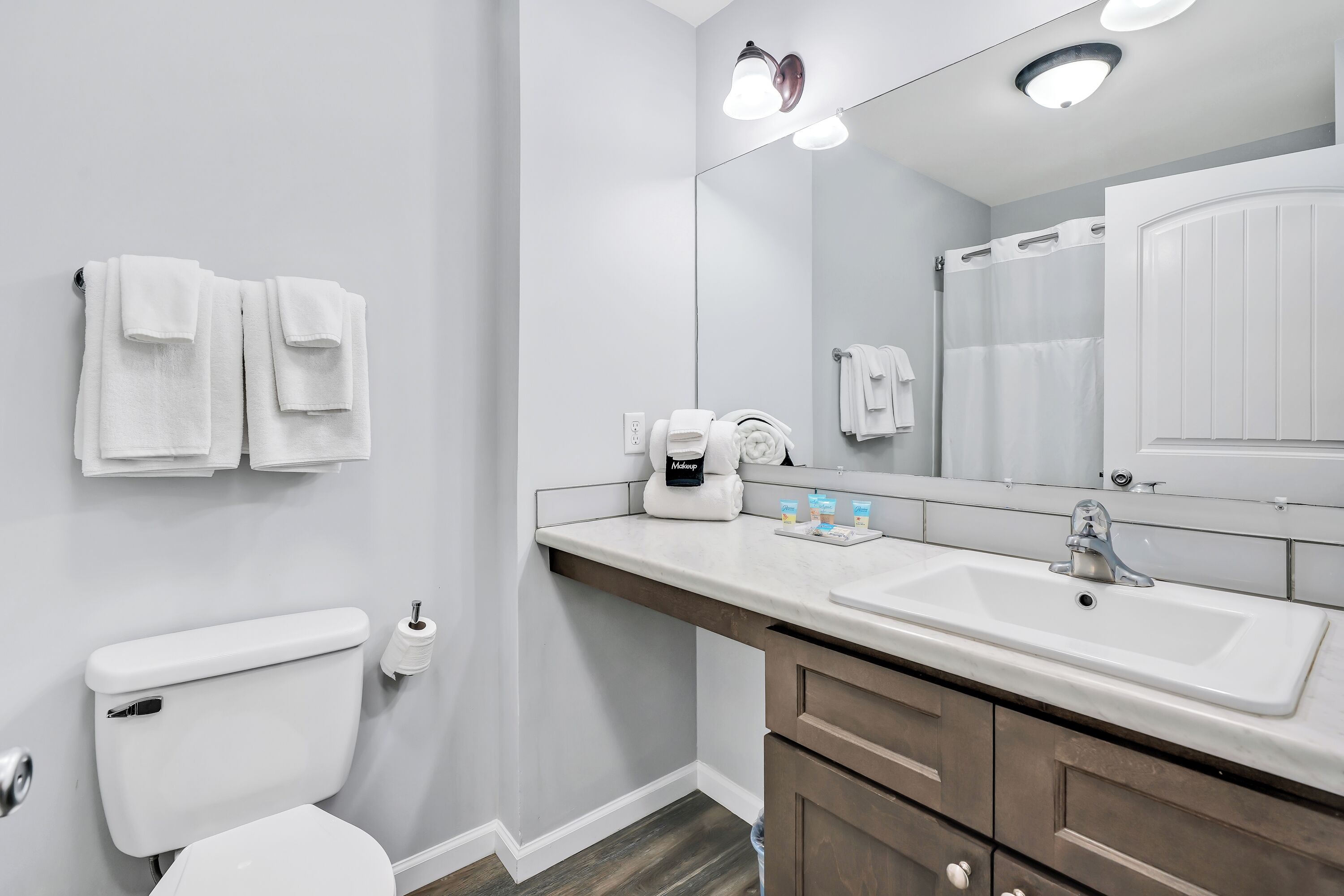A bathroom with a white sink, a mirror, a toilet, and a towel rack with towels.