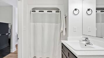 Un bagno moderno con doccia, lavandino e specchio.