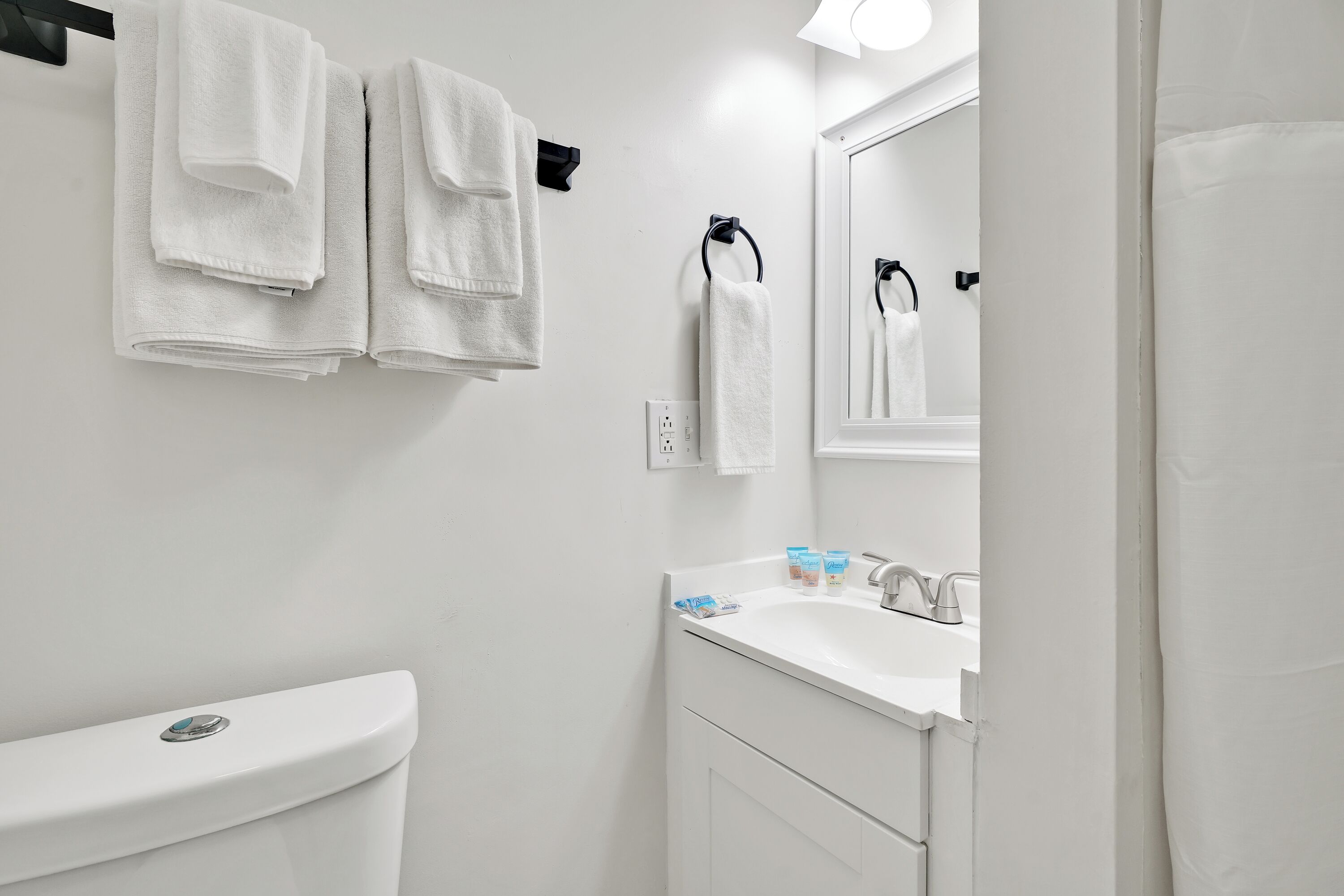A bathroom with a toilet, sink, and two towel racks.