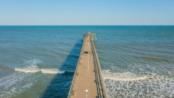 A long pier extending into calm waters with a clear sky above.