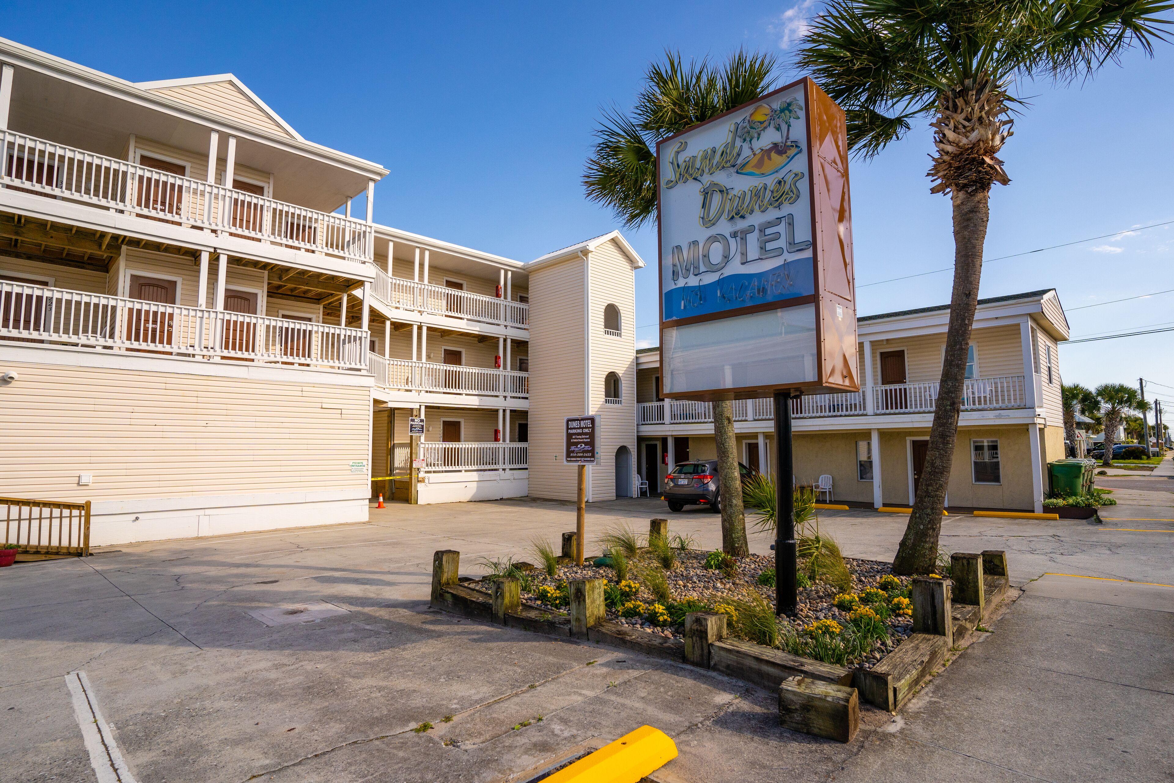 A motel with a signboard, a parking lot, and a building with balconies.