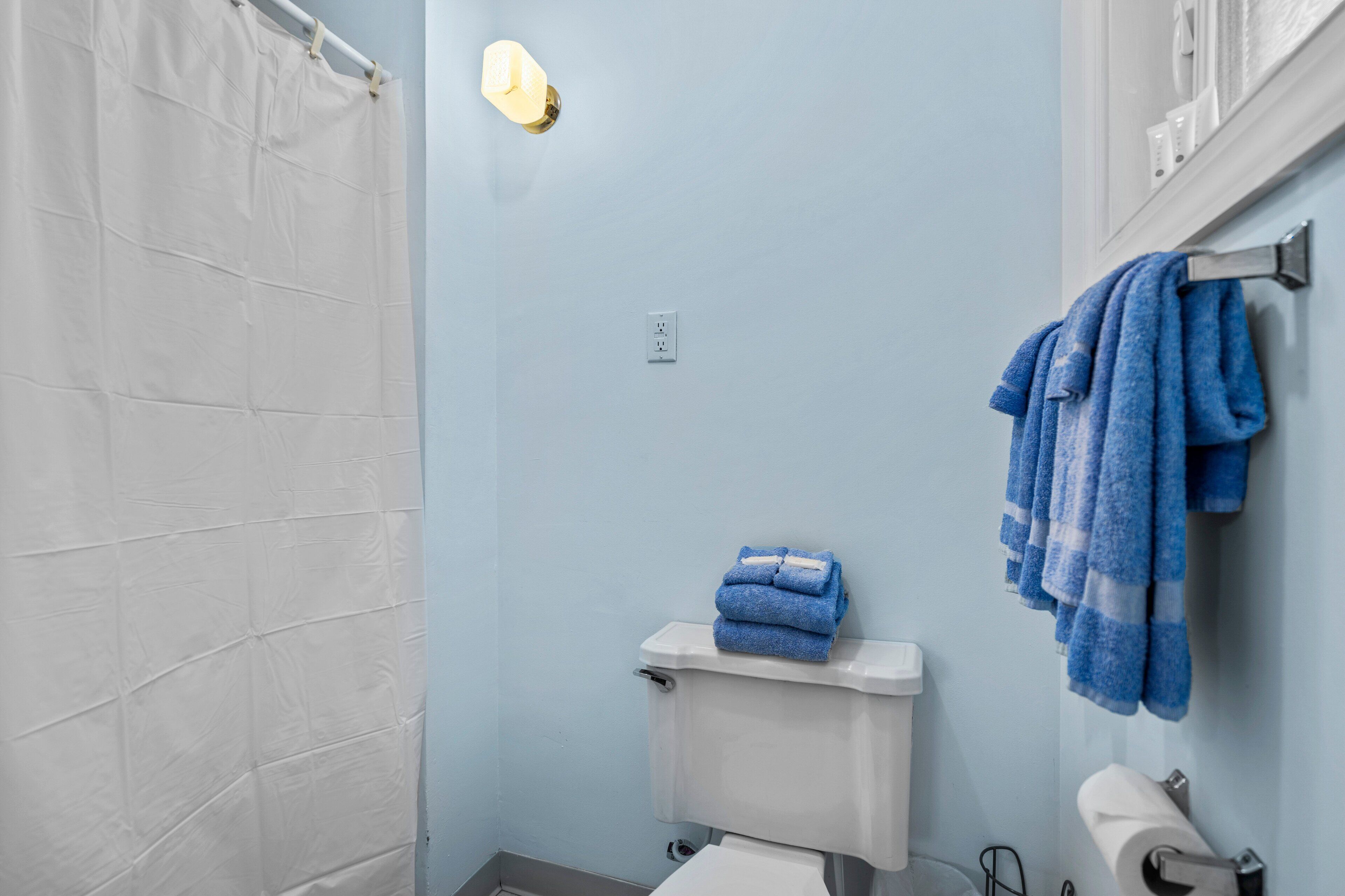 A bathroom with a white shower curtain, a toilet, and a sink.