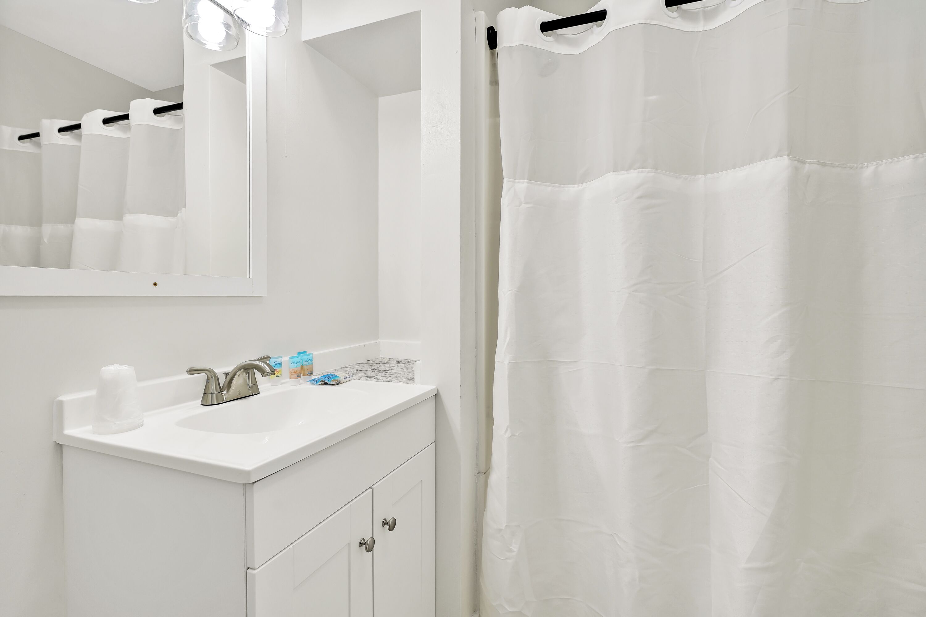 A bathroom with a white sink, mirror, and shower curtain.