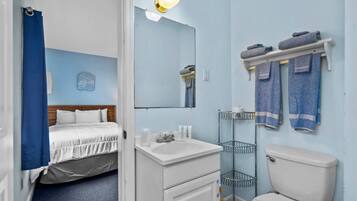 Une salle de bain d’hôtel équipée d’un lit, d’un lavabo, d’un miroir et de serviettes.