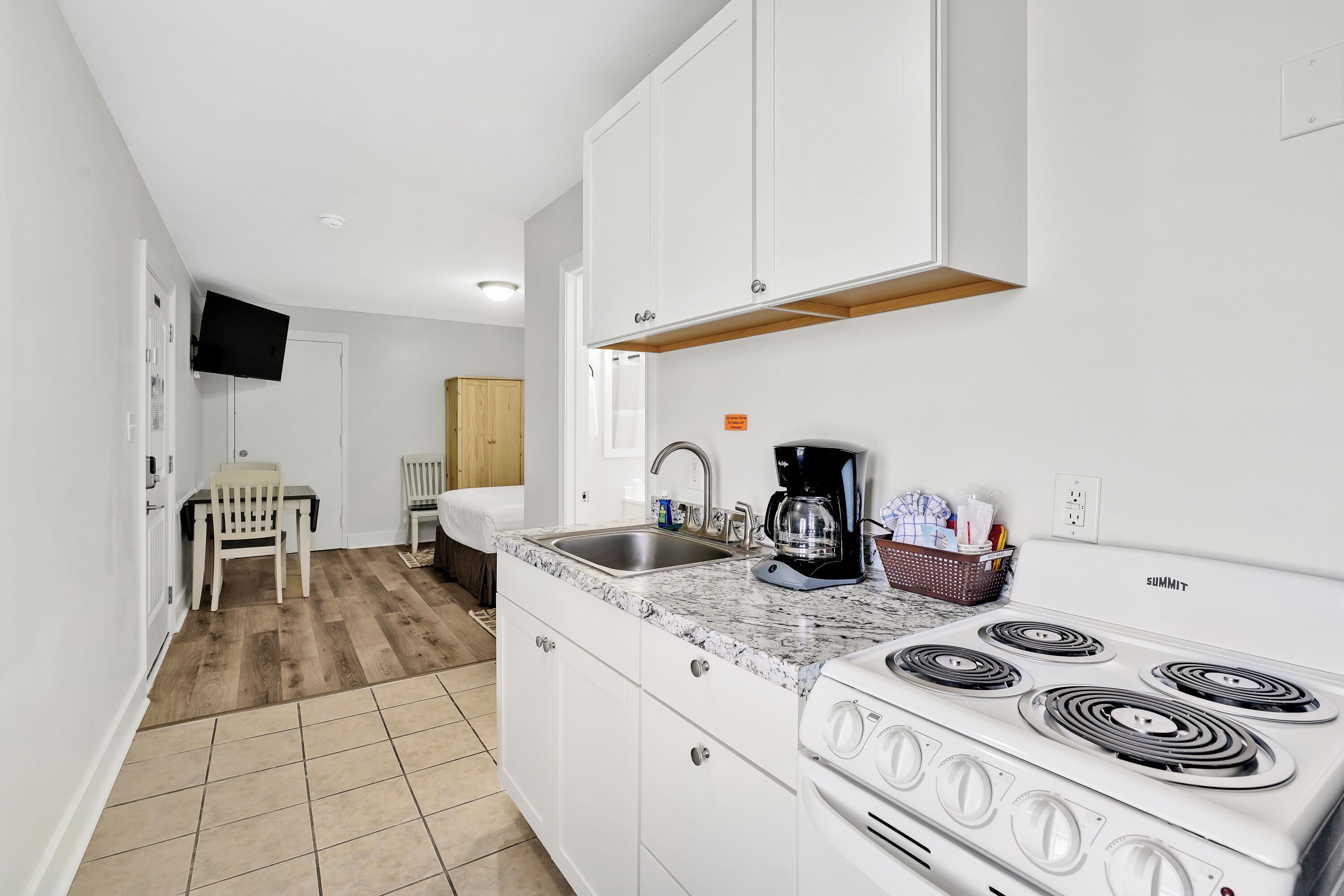 A compact kitchen with white cabinets, a built-in stove, and a sink.