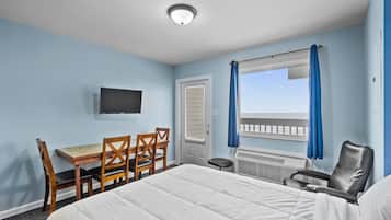 A hotel room with a bed, a desk with chairs, a television, and a window with curtains.