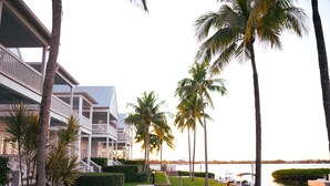 Ein Resort mit Poolbereich, Palmen und Blick auf das Wasser.
