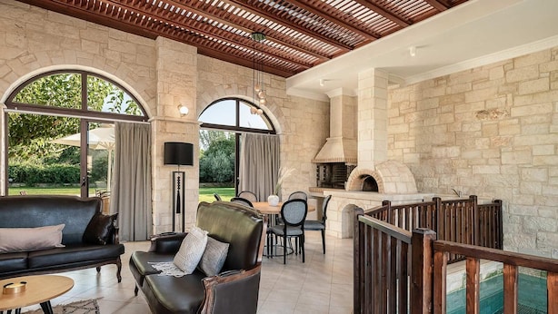 Un patio espacioso con chimenea de piedra, asientos de cuero y zona de comedor.